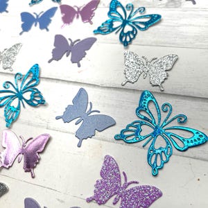 May include: Assortment of colorful butterfly cutouts, including silver, purple, blue, and teal. Some butterflies have glitter accents.