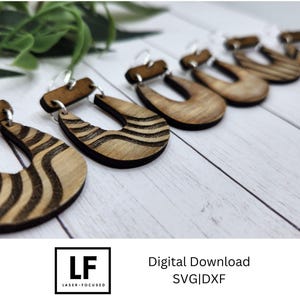 May include: Five pairs of wooden earrings with a wavy pattern. The earrings are brown and have a natural wood finish. The earrings are displayed on a white surface.