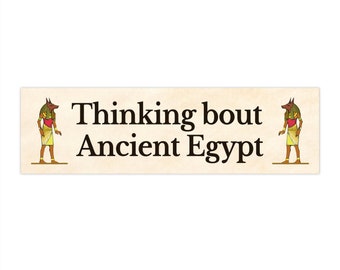 Könnte beinhalten: Ein beiger Banner mit einer Anubis-Illustration auf jeder Seite und dem Text "Thinking bout Ancient Egypt".