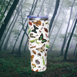 May include: A white stainless steel tumbler with a clear lid and straw, featuring a detailed all-over print of various insects including butterflies, moths, beetles, caterpillars, and a praying mantis scattered across the entire surface.