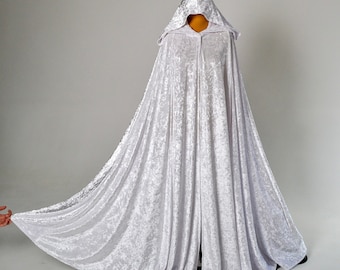 May include: A white velvet hooded cape with a long train. The cape is made of a soft, luxurious fabric and has a classic design.