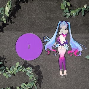 May include: A purple acrylic stand with a slot and a colourful anime-style figure. The figure has long blue and pink hair, and is wearing a white, purple, and pink outfit. The stand is round and the figure is standing upright.