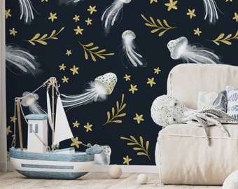 May include: A navy blue wall with a repeating pattern of white jellyfish, gold stars, and gold leaf accents. A white sofa with decorative pillows and stuffed animals sits in front of the wall. A toy sailboat and a pink starfish are on the floor.