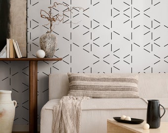 May include: A living room with a light beige couch, a wooden coffee table, and a vase with dried branches. The wall is covered in a white wallpaper with a black geometric pattern.