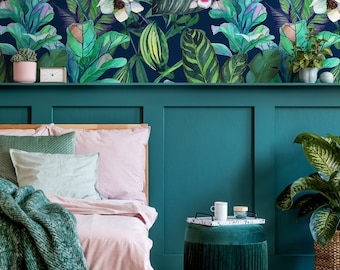 May include: A bedroom with a teal green headboard and a pink and white striped bedspread. The wall behind the bed is covered in a tropical floral wallpaper with large green leaves and white flowers. A small green velvet ottoman sits in front of the bed with a white mug and a small tray on top.