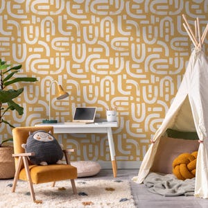 May include: A yellow and white geometric patterned wallpaper with a white desk, a yellow chair, a gray plush toy, a white laptop, a white lamp, a white teepee tent, and a yellow and white throw pillow.