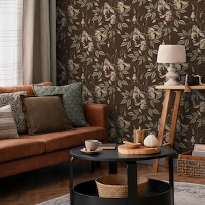 Könnte beinhalten: Ein braunes Ledersofa mit Kissen vor einer braunen Tapeten mit Blumenmuster. Ein schwarzer Couchtisch mit einem Holzbrett, einem weißen Kürbis und einer Tasse Kaffee steht vor dem Sofa.