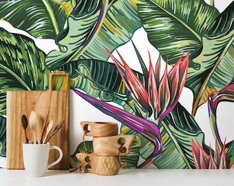 May include: A white ceramic mug with a wooden cutting board and wooden spoons behind it. The background is a white wall with a tropical leaf pattern featuring green, yellow, and pink colors.