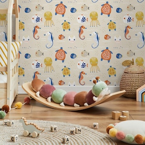 Puede incluir: Un papel tapiz beige con un patrón repetitivo de criaturas marinas, incluyendo peces, caballitos de mar, tortugas y medusas. El papel tapiz está decorado con colores azul, amarillo, naranja y marrón.