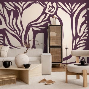 May include: A living room interior with a white sofa, a wooden coffee table, and a white ottoman. The wall is decorated with a large-scale abstract floral mural in shades of purple and white.