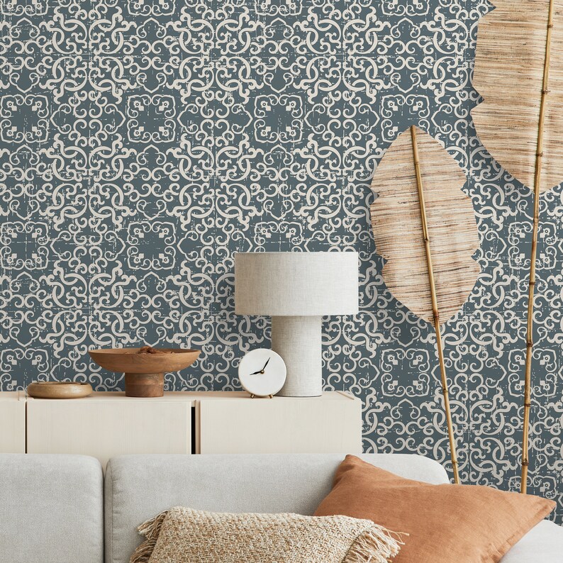 K&ouml;nnte beinhalten: Ein Wohnzimmer-Interieur mit einer grauen gemusterten Tapete, einer wei&szlig;en Lampe mit einem wei&szlig;en Lampenschirm, einer wei&szlig;en Uhr, einer Holzschale, einem wei&szlig;en Schrank und einem grauen Sofa mit braunen und beigefarbenen Kissen.