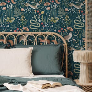 Puede incluir: Un dormitorio azul verdoso con una cama que presenta una cabecera estampada y una funda n&oacute;rdica azul verdosa. La cabecera presenta un patr&oacute;n caprichoso de criaturas del bosque, hongos y plantas. La cama est&aacute; decorada con dos almohadas y un libro.