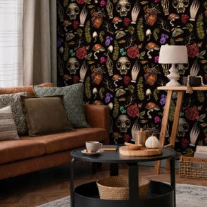 May include: A black and white wallpaper with a repeating pattern of skulls, hearts, flowers, and mushrooms. The wallpaper is in a living room setting with a brown leather couch and a coffee table.