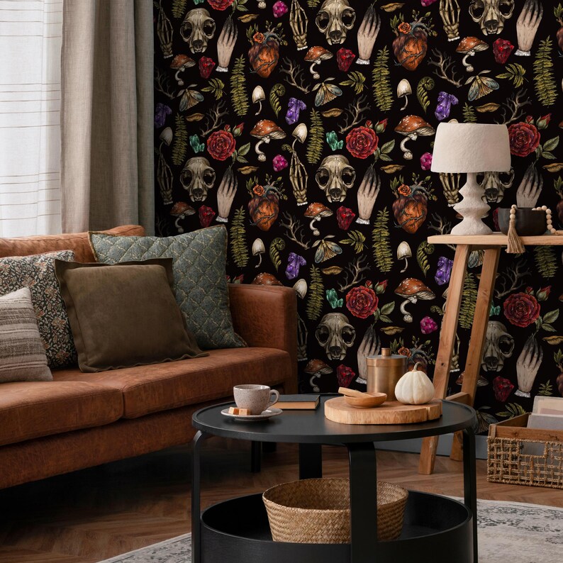May include: A black and white wallpaper with a repeating pattern of skulls, hearts, flowers, and mushrooms. The wallpaper is in a living room setting with a brown leather couch and a coffee table.