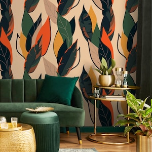 May include: A stylish living room with a green velvet sofa, ottoman, and cushion. The wallpaper features a repeating pattern of large, stylized leaves in green, orange, and yellow. Gold tables and plant pots provide a luxurious touch to the room's decor.