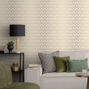 May include: A white sofa with gold and white patterned wallpaper in the background. The sofa has green and black patterned throw cushions. A black lamp with a gold base sits on a black shelf in the foreground.