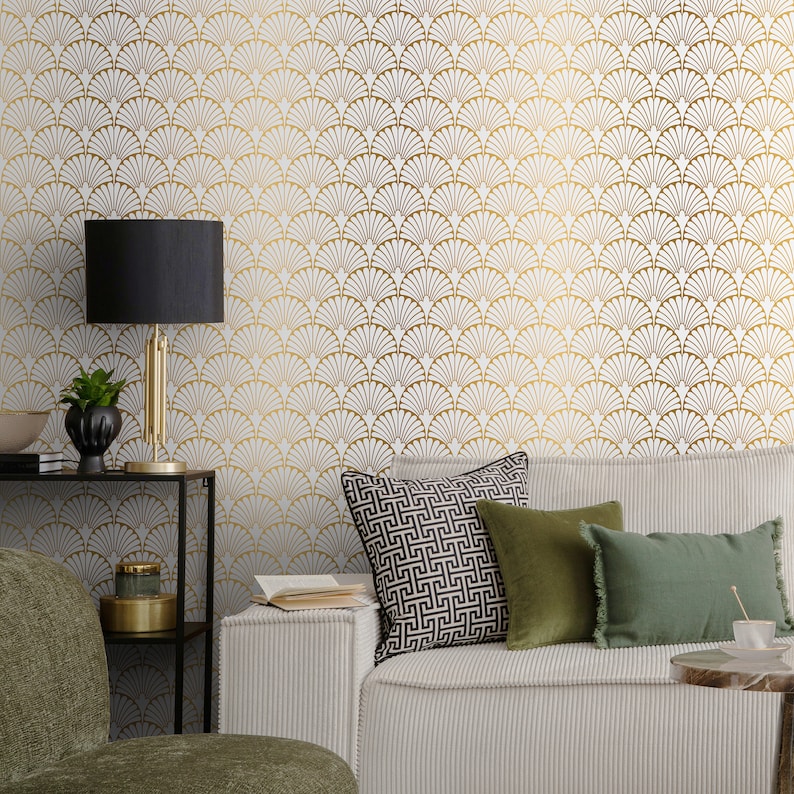 May include: A white sofa with gold and white patterned wallpaper in the background. The sofa has green and black patterned throw cushions. A black lamp with a gold base sits on a black shelf in the foreground.