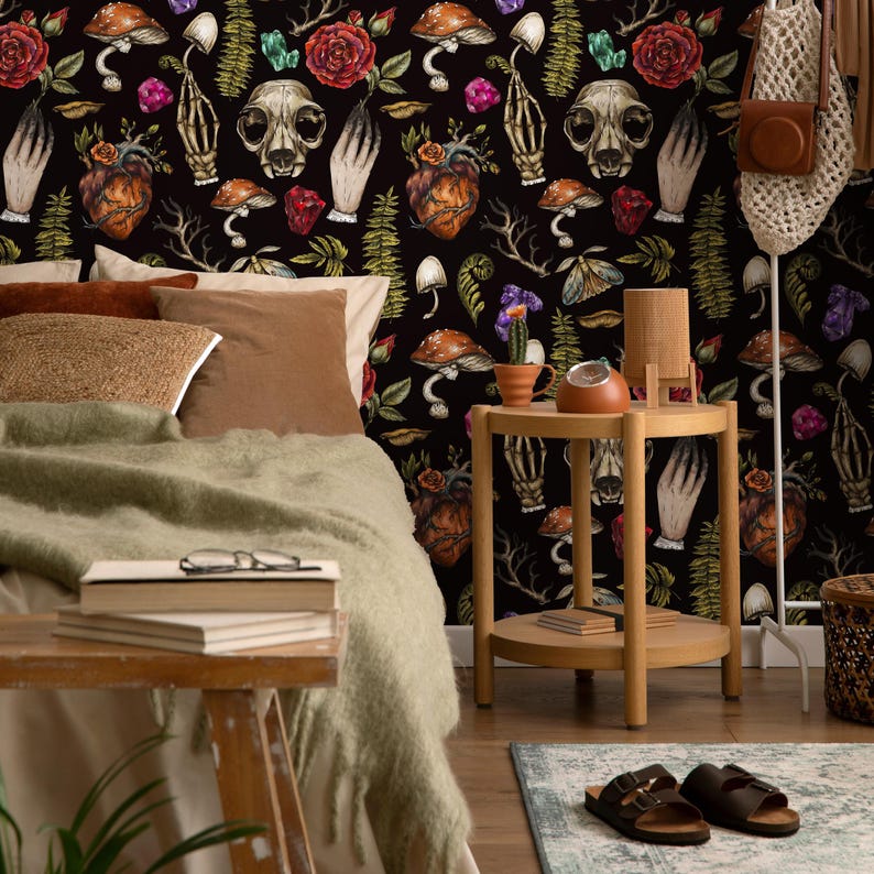 May include: A black and white wallpaper with a repeating pattern of skulls, hearts, mushrooms, flowers, and hands. The wallpaper is in a bedroom setting with a bed, side table, and rug.