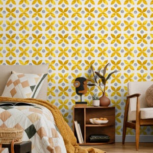 May include: A bedroom scene with a bed featuring a patterned quilt and pillow, a wooden bedside table, and patterned wallpaper. The wallpaper has a repeating pattern of yellow floral shapes and grey dots.