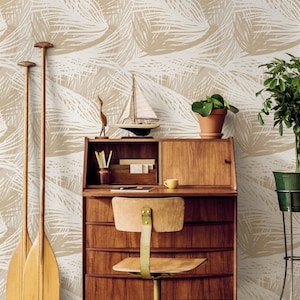 May include: A beige and white patterned wallpaper with a wooden desk, chair, and potted plants. The desk has a small shelf above it and a drawer below. There are two wooden paddles leaning against the wall.