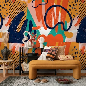 May include: A modern living room scene featuring a mustard yellow bench with decorative pillows, a black metal shelf, and a colorful abstract art mural in the background. The mural has orange, blue, and teal brushstrokes.