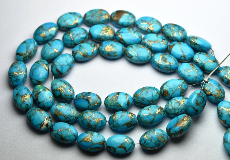 Op de afbeelding: Snoer van turquoise ovale kralen met goudkleurige adering. De kralen zijn aan elkaar geregen en tonen hun gepolijste, gladde oppervlakken. De gouden adering cre&euml;ert een opvallend contrast met de blauwgroene tint, wat wijst op een natuursteen.
