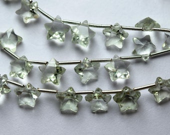 Puede incluir: Una hebra de cuentas de piedras preciosas de color verde claro en forma de estrella enhebradas en un alambre de plata.