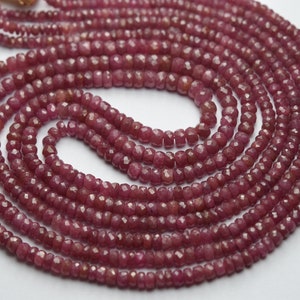 Pode incluir: Um fio de contas de rubi vermelho-escuro, facetadas e polidas, enfiadas em um cordão fino. As contas são pequenas e de tamanho uniforme, criando um visual delicado e elegante.