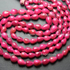 May include: A strand of pink gemstone beads in a teardrop shape. The beads are strung on a clear thread and are arranged in a loose, flowing pattern.