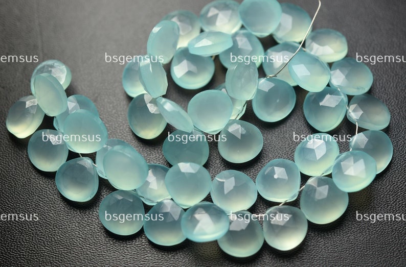 May include: A strand of light blue gemstone beads, each bead is faceted and has a rounded, slightly oval shape. The beads are strung on a thin wire.