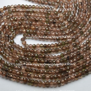 May include: A strand of brown and green faceted gemstone beads. The beads are approximately 4mm in diameter and have a smooth, polished finish.
