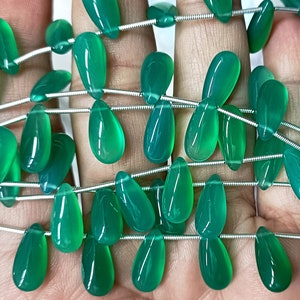 May include: A strand of green gemstone beads in a teardrop shape. The beads are strung on a silver wire.