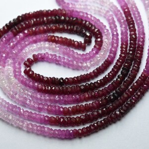 Puede incluir: Varias hebras de cuentas de piedras preciosas facetadas en tonos rosa y rojo dispuestas en espiral. Las cuentas varían de rosa claro a rojo intenso, creando un efecto degradado. Las cuentas son pequeñas y de tamaño uniforme.