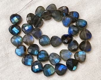 May include: A collection of heart-shaped labradorite beads. The beads are multi-faceted and exhibit a play of colours, including blues, greens, and greys. The beads are strung on a thin wire, ideal for crafting jewellery.