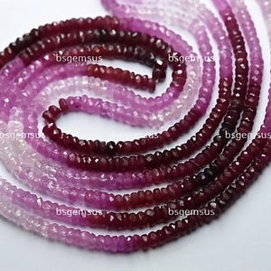May include: A strand of faceted pink and red gemstone beads. The beads are graduated in size, with the larger beads at the bottom of the strand. The beads are all faceted, giving them a sparkly appearance.