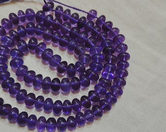 May include: A strand of purple amethyst beads, each bead is faceted and has a slightly oval shape.