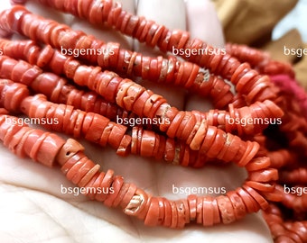 May include: A strand of coral beads, made of stacked, flat, orange-red coral pieces. The beads are strung on a clear thread and are approximately 1/2 inch in diameter.