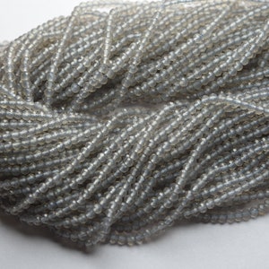May include: A strand of gray faceted glass beads. The beads are round and have a smooth, polished finish.