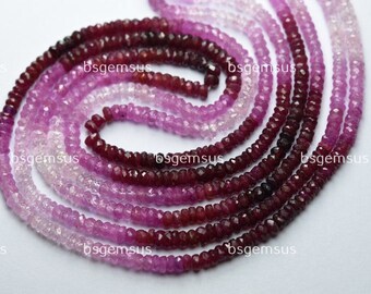 May include: A strand of pink and red gemstone beads. The beads are faceted and have a graduated color from light pink to dark red.