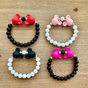May include: Four bracelets with black and white beads and silicone Mickey Mouse ears in red, pink, black, and white.