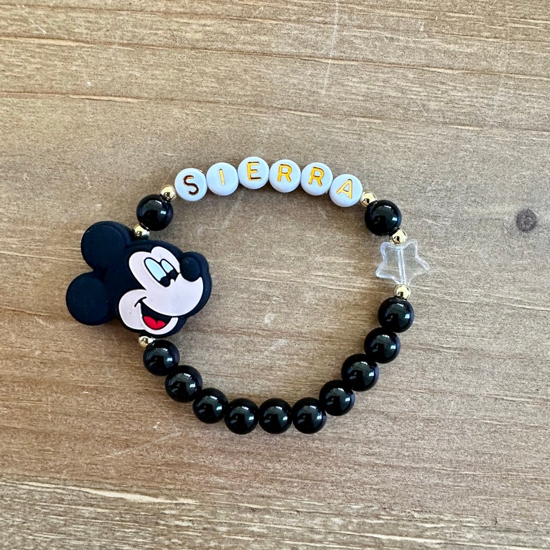 Puede incluir: Pulsera de cuentas negras con un dije de Mickey Mouse y cuentas blancas que deletrean el nombre "SIERRA".