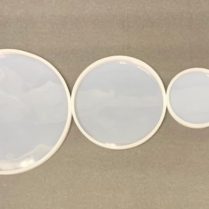 May include: Four white round silicone molds of varying sizes. The molds are arranged in a line from largest to smallest.