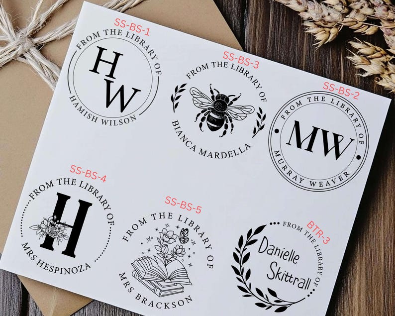 May include: Six different black and white rubber stamps with text that reads "From the Library of" and a name. The stamps are on a white background.