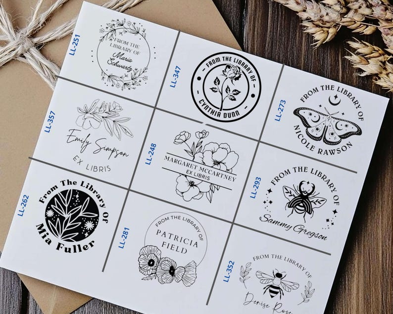 May include: Nine black and white custom bookplate stamps with different designs and names. The stamps feature floral designs, a bee, a butterfly, and a crescent moon.
