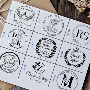 May include: A white sheet of paper with nine different black and white bookplate designs. Each design features a different initial, name, and text. The text includes "Ex Libris", "From the Library of", and "This Book Belongs To".