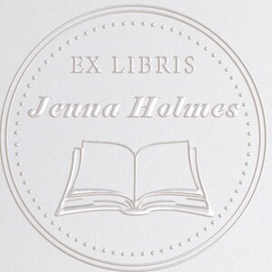 Puede incluir: Un c&iacute;rculo blanco con un borde punteado, que contiene el texto "Ex Libris Jenna Holmes" y una imagen de un libro abierto.
