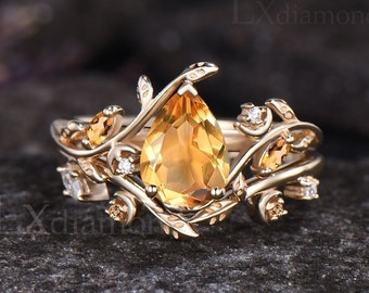 Könnte beinhalten: Ein goldener Ring mit einem birnenförmigen Topas-Edelstein, umgeben von kleineren Diamanten und einem filigranen Rankendesign.