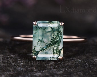 May include: A rose gold ring with a large, rectangular, green moss agate gemstone. The gemstone has a unique, natural pattern of white and green.