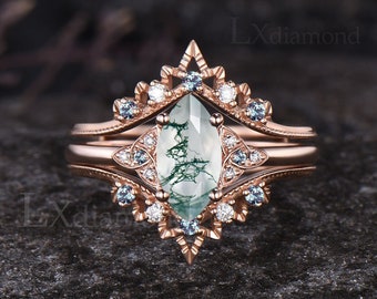 May include: A rose gold engagement ring set with a moss agate center stone and a delicate, intricate design featuring smaller diamonds and blue topaz accents.