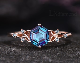 May include: A rose gold ring with a blue hexagonal gemstone surrounded by smaller clear gemstones. The ring features a delicate, intricate design.